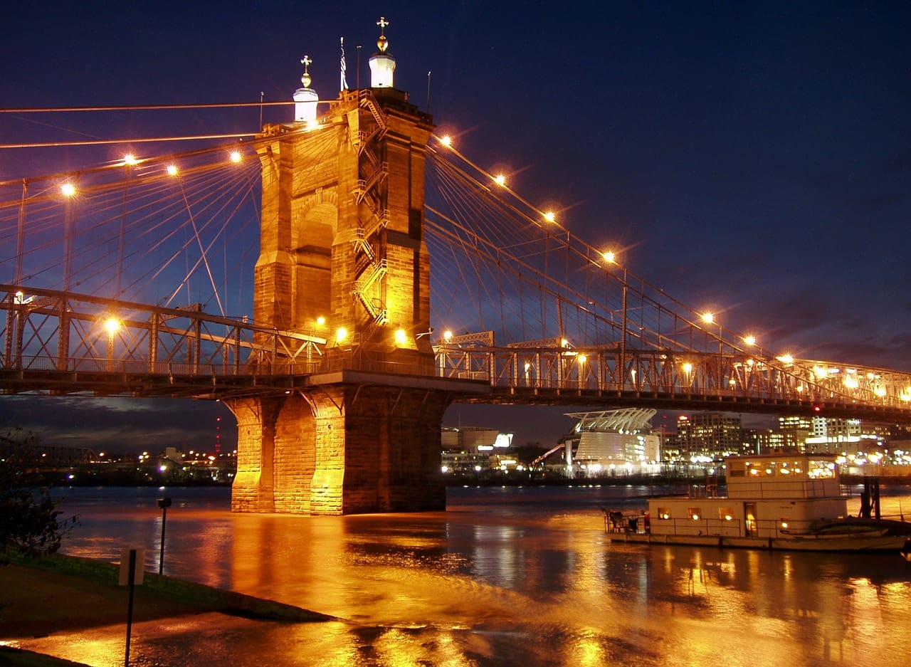 A bridge with lights hanging over it and water