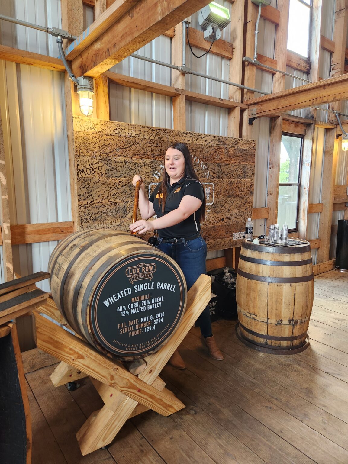 A woman standing next to a barrel in a room.