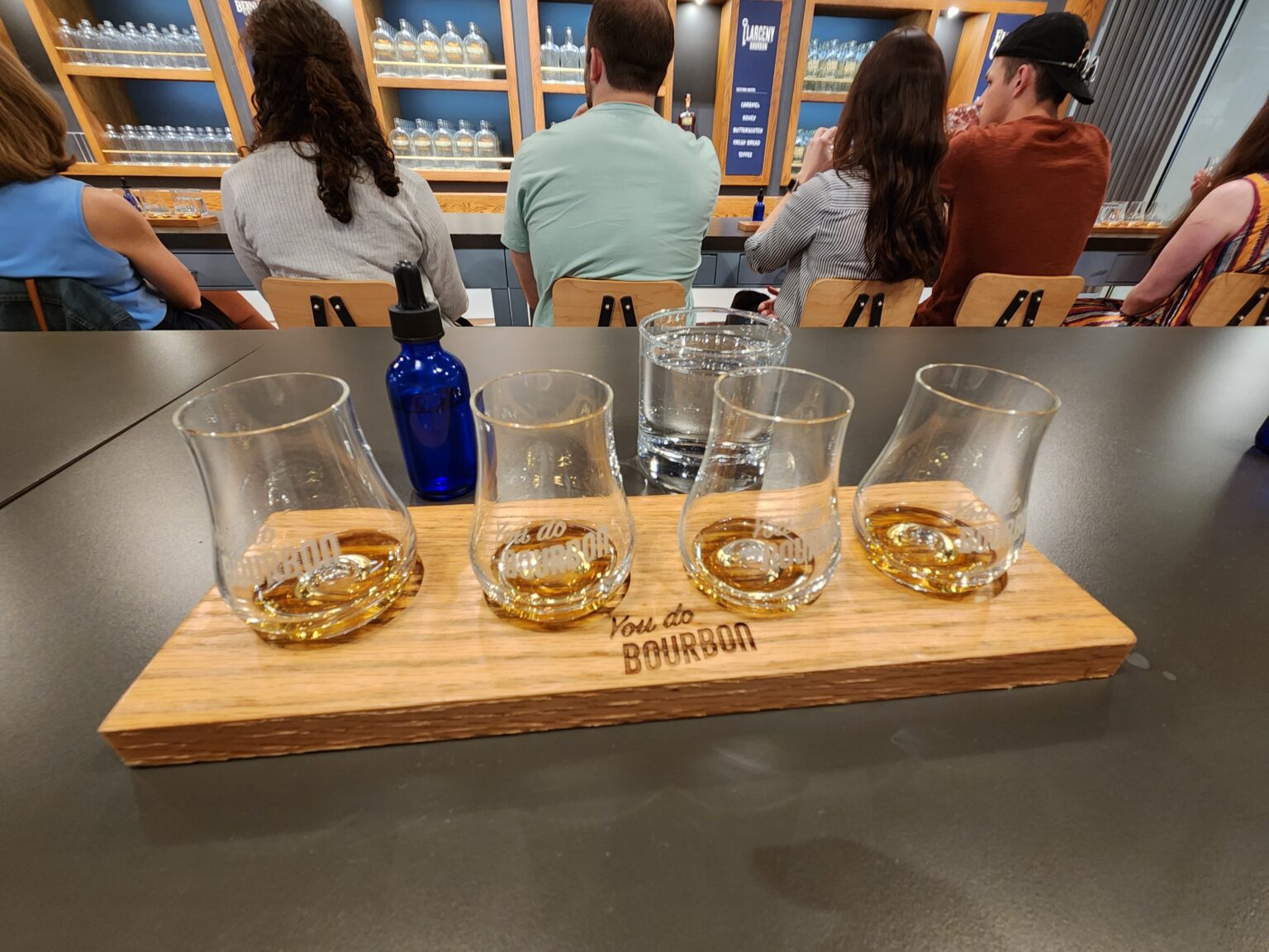 A wooden tray with four glasses of beer on it.