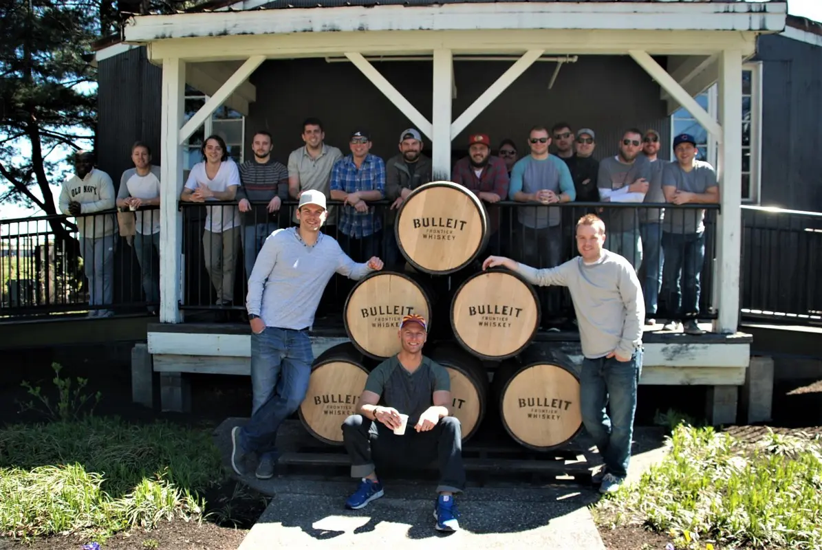 A group of people standing around some barrels.