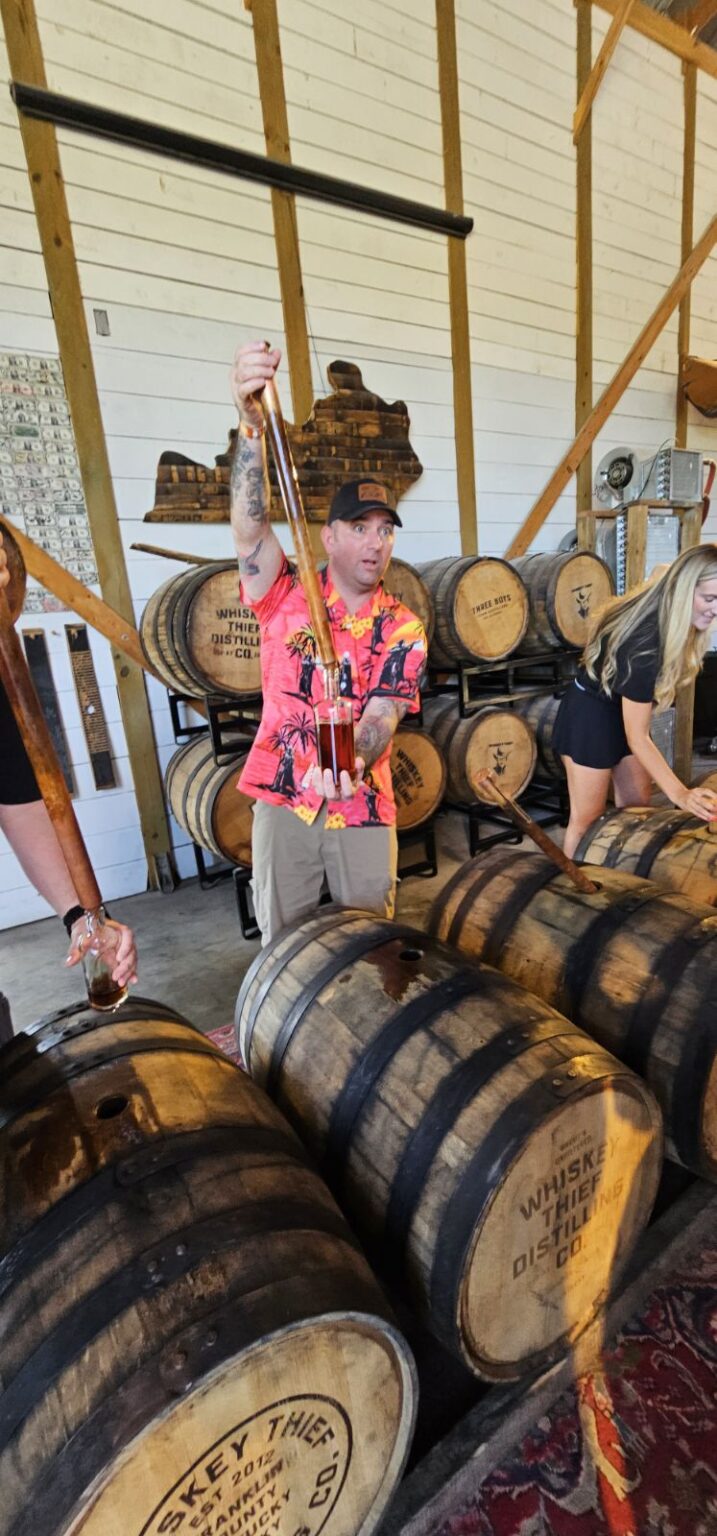 A group of people standing around barrels in a room.